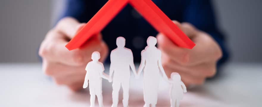 Businessman Protecting Family Figures With Red Roof